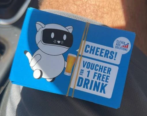 A stack of blue cards with the robo-cat holding a beer: “Cheers! Voucher for 1 free drink”