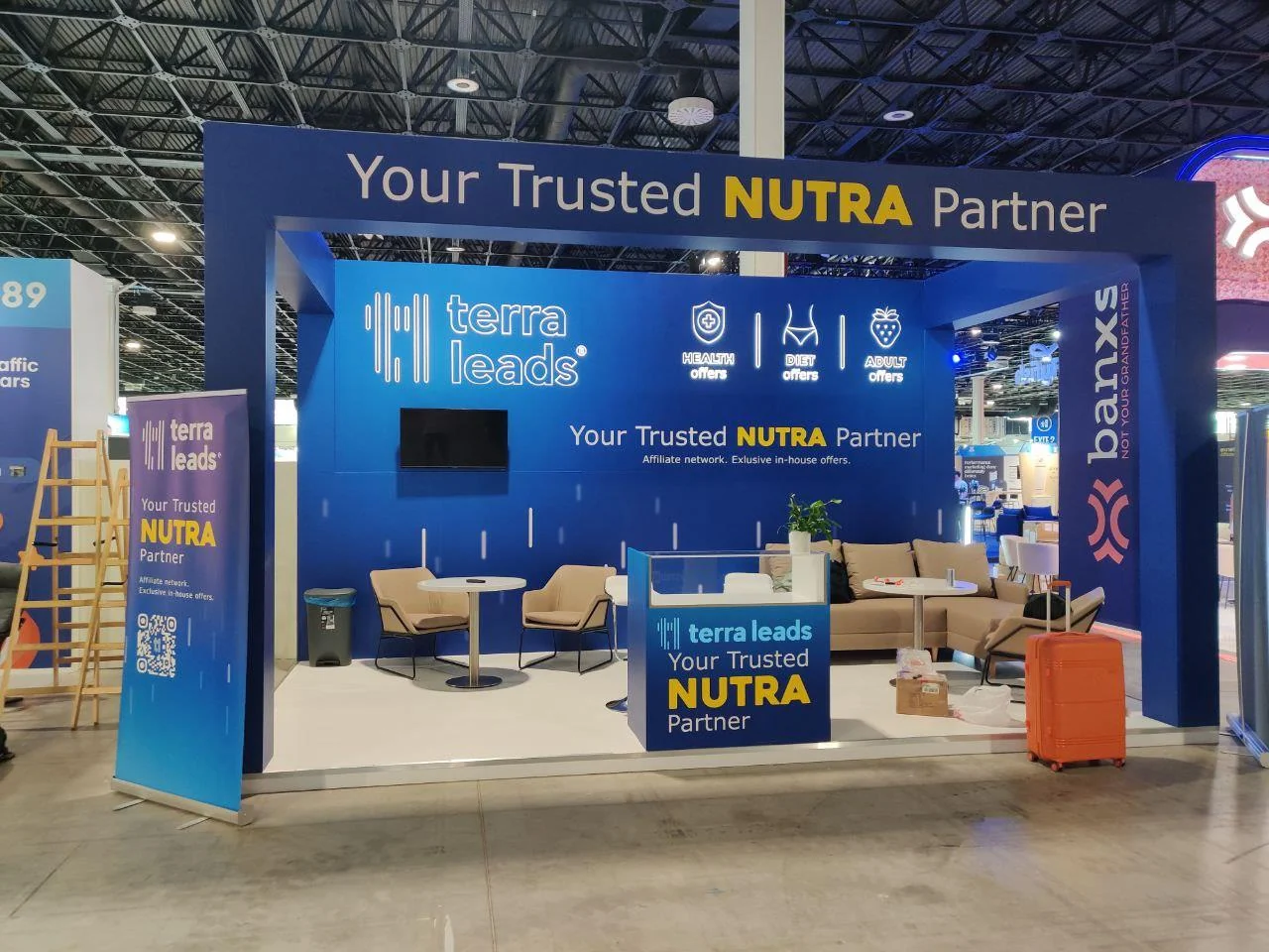 TerraLeads stand at Affiliate World Europe: blue walls reading “Your Trusted NUTRA Partner”, lounge chairs and a counter